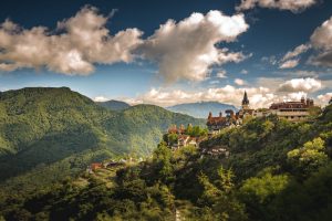 aerial-shot-small-village-hill-surrounded-by-forested-mountains